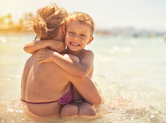 Boy hugs mum on beach